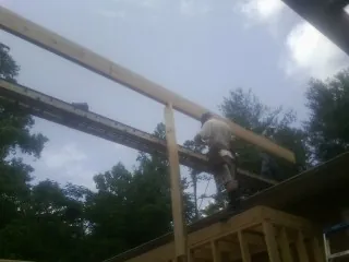 Carpenter setting a ridge beam over a new addition frame — Ice Dam Removal by Roofing Brothers in Little River