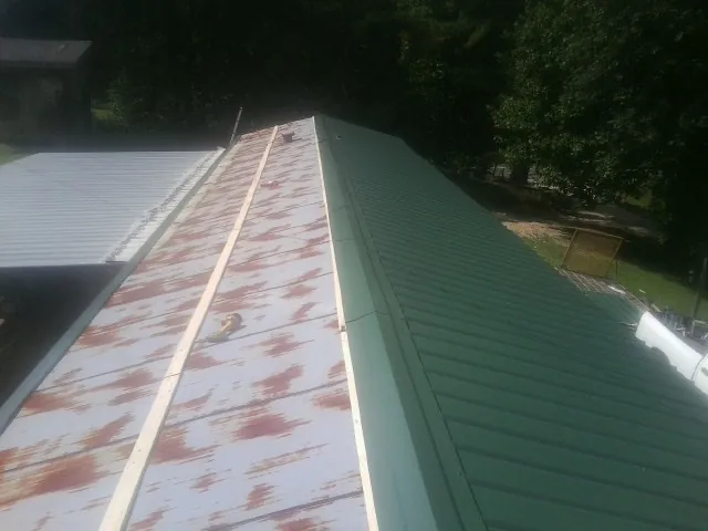 Old rusted panels beside newly installed green metal roofing — Wind Damage Roof Repair by Roofing Brothers in Little River