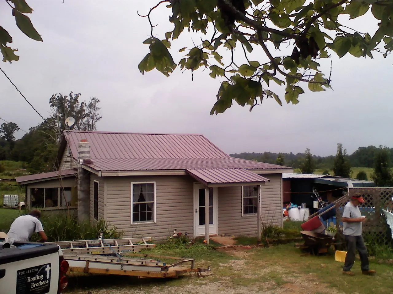 Crew finishing a mauve metal roof on a small farmhouse in Little River