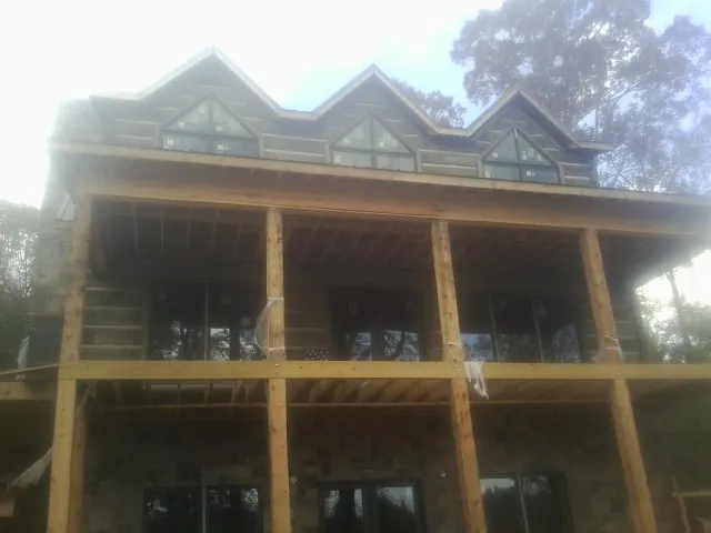 Dormers and porch framing on a large log home under construction — Roof Coating work by our crew in Little River
