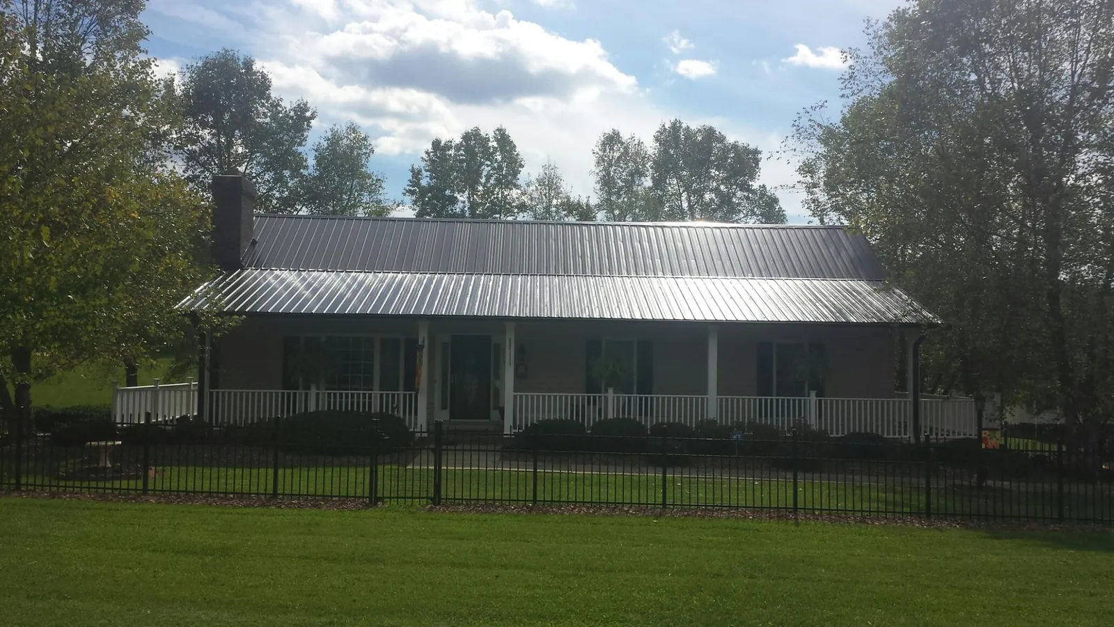 Gray metal roof on a brick ranch with a full width front porch — Gutter Guard Installation work by our crew in Little River