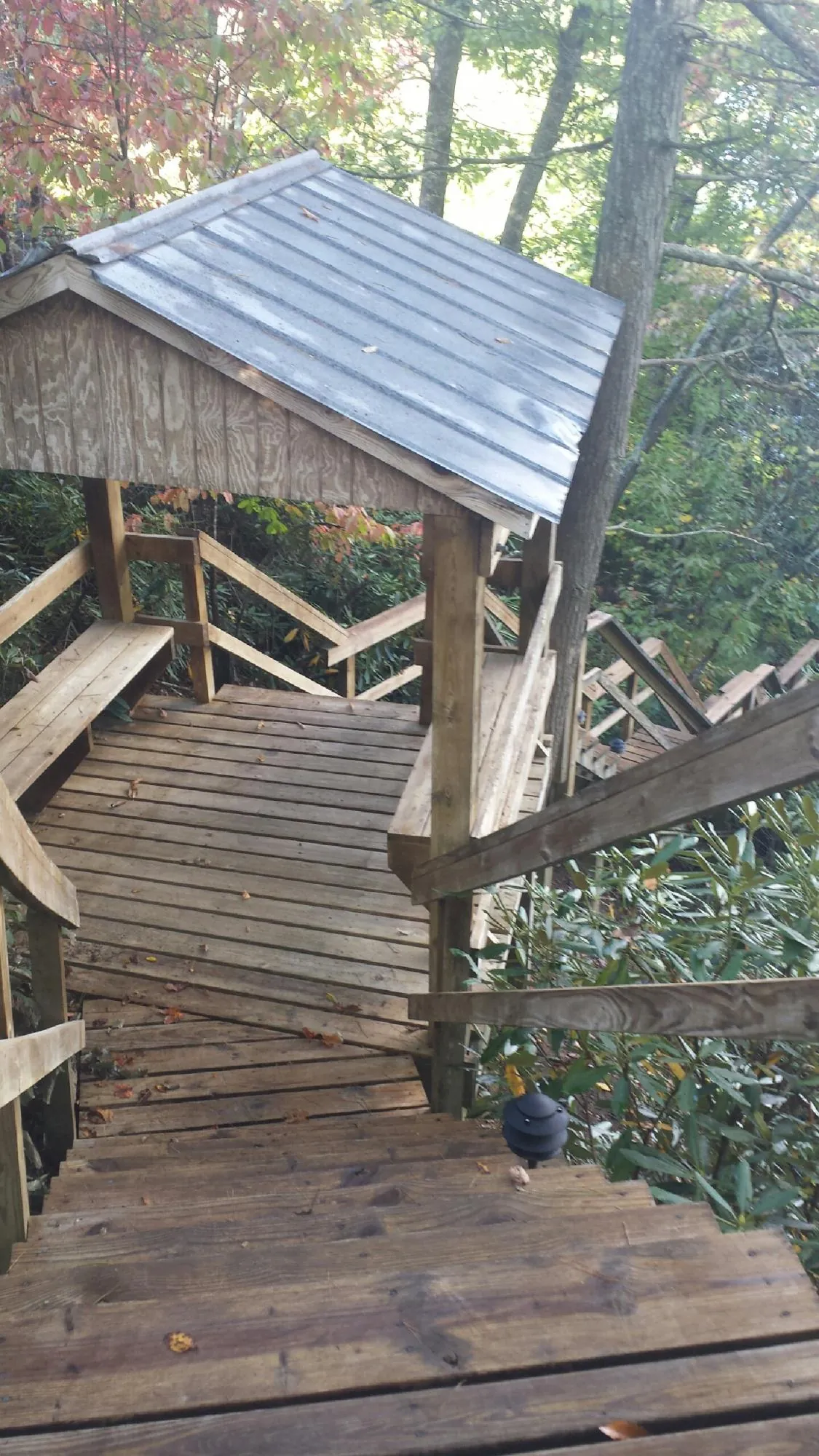 Metal roofed shelter over wooden steps on a wooded walkway — Skylight Repair & Installation work by our crew in Little River