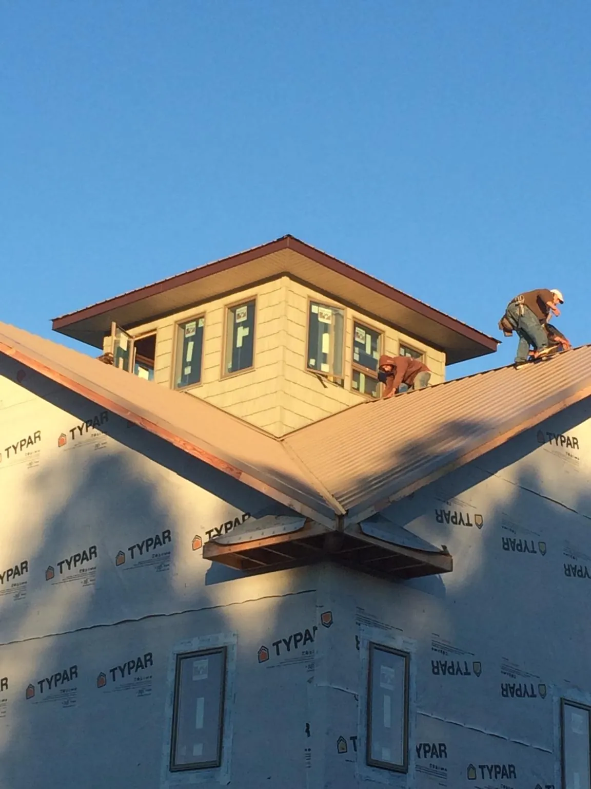 Roofers working around a rooftop cupola on a new metal roof at sunset — Roof Waterproofing in Little River by Roofing Brothers